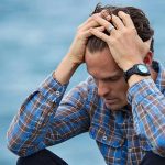 Stressed man holding his head in frustration, representing burnout symptoms