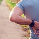 Man outside holding his back in pain, symbolizing chronic tension and counselling support in Nanaimo