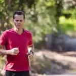 A man is running on a trail in the woods.