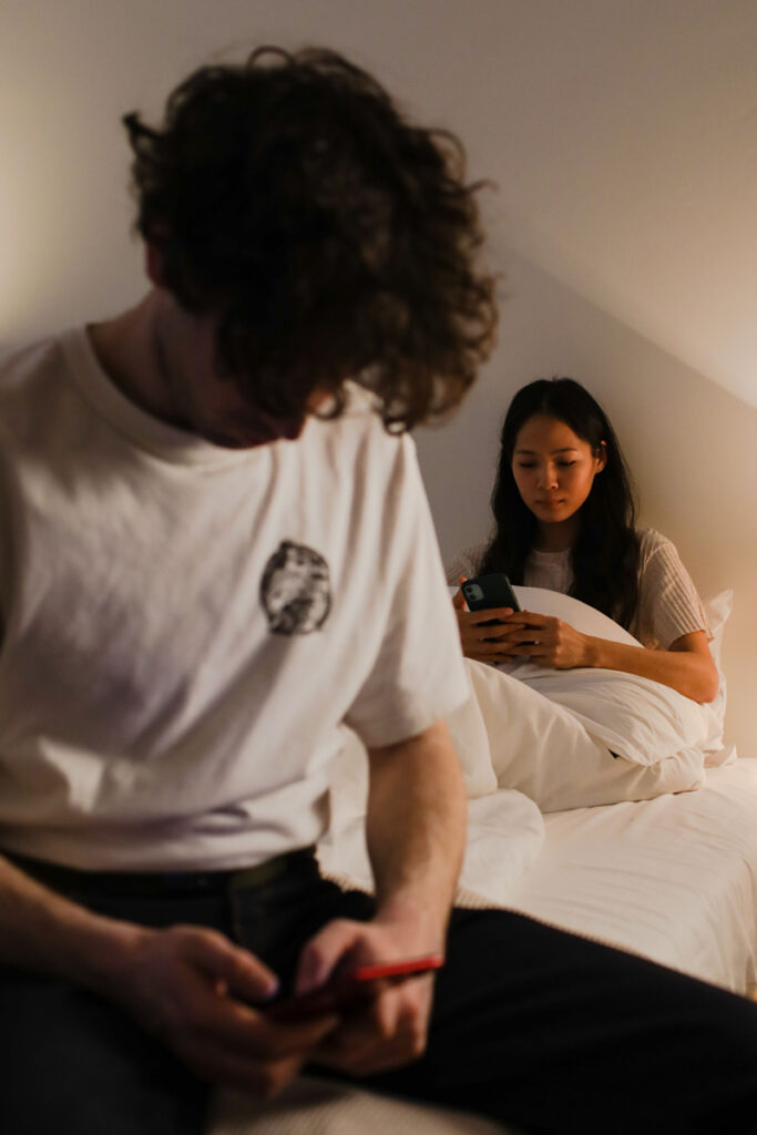 Man and woman sitting in bedroom not making eye contact, showing emotional disconnection