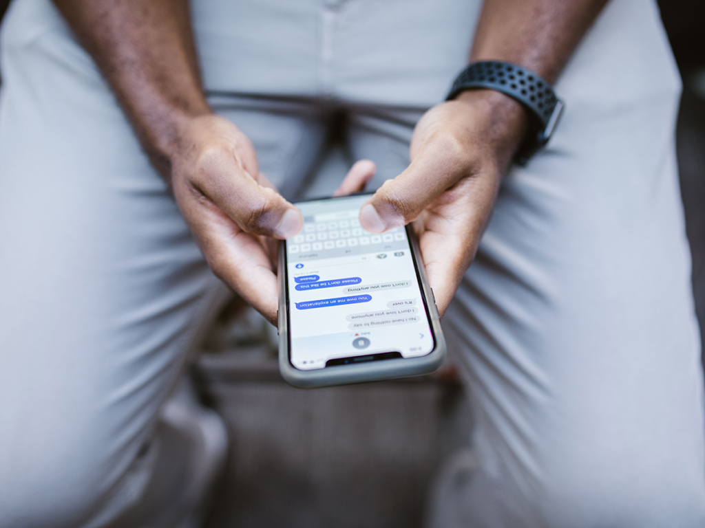 Man calmly texting his ex-wife to coordinate a co-parenting schedule after divorce